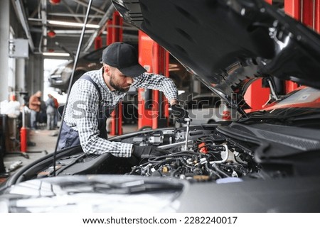 Adult man in blue colored uniform works in the automobile salon Royalty-Free Stock Photo #2282240017