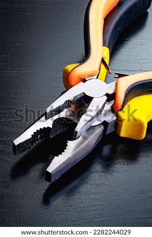Two pliers, tools on a black wooden table close up Royalty-Free Stock Photo #2282244029