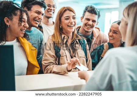 Group of young people takes room key card at check-in of youth hostel guest house - Happy tourists talking with receptionist at hotel lobby - Summer vacations and tourism concept Royalty-Free Stock Photo #2282247905