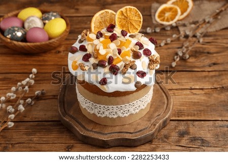 Delicious Easter cake with dried fruits, willow branches and painted eggs on wooden table
