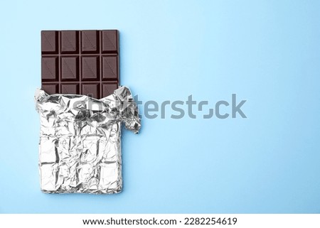 Tasty chocolate bar on light blue background, top view. Space for text Royalty-Free Stock Photo #2282254619