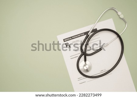Top view of a stethoscope over the medical prescription sheet on a green background. Space for text. Medical and healthcare concept Royalty-Free Stock Photo #2282273499