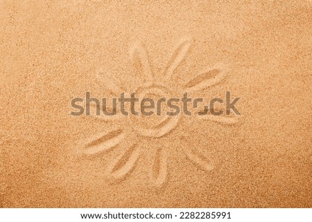 The sun is painted on the sand. Sand texture, natural background. Top view.