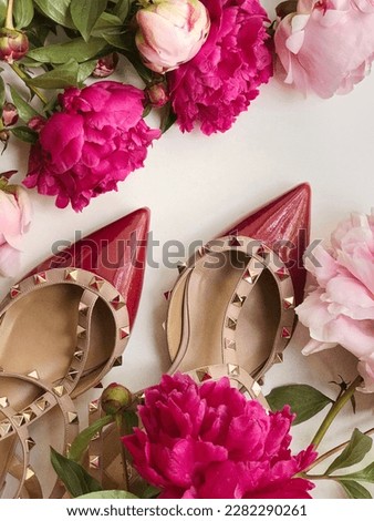 Red shoes on a flower background. Beauty and fashion concept. Woman stylish heels with decorations. Peony pink flowers.