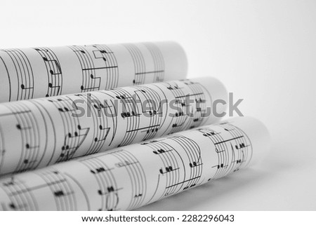 Rolled sheets with music notes on white background, closeup Royalty-Free Stock Photo #2282296043