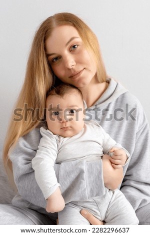 Mom and baby play on the bed. Mother and son, happy family, beautiful blonde girl and cute baby.