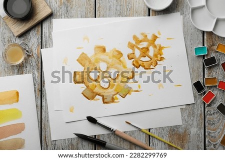 Flat lay composition with watercolor painting of gears and paints on light grey wooden table