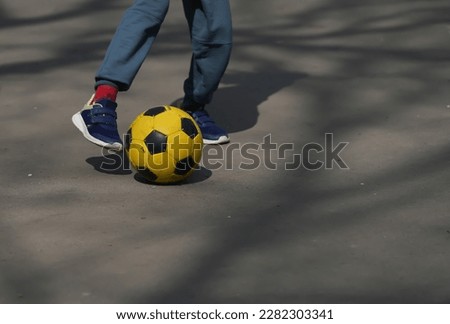 child playing on the path of a park with a ball. detail.