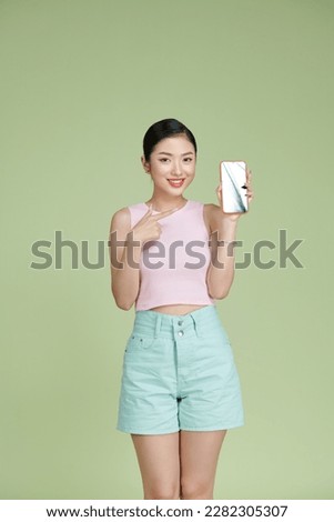 Young asian girl using the phone on green background
