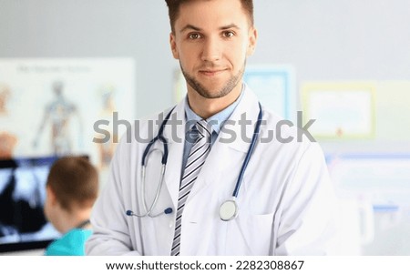 Portrait of smiling young doctor with a stethoscope on background of office in clinic. Royalty-Free Stock Photo #2282308867