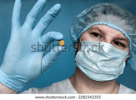 Removed Stone 14 mm from the kidney, in the doctor's hands. Human urolithiasis. Phosphate or oxalate kidney stone. Urologist surgeon demonstrates a kidney stone. Doctor in medical uniform. Royalty-Free Stock Photo #2282342355