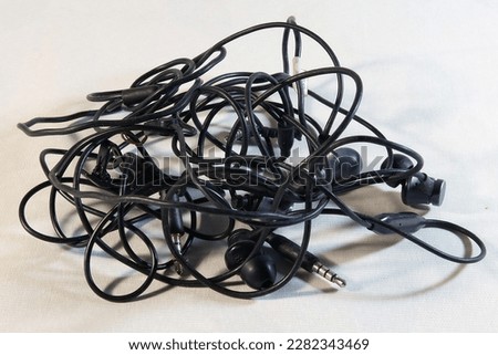 Tangled headphone wires for phone close-up on white background Royalty-Free Stock Photo #2282343469