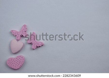 Love and romance, Small butterflies, hearts, spots scattered at the edge of a white background, photographed from above, in pink, showing love and romance