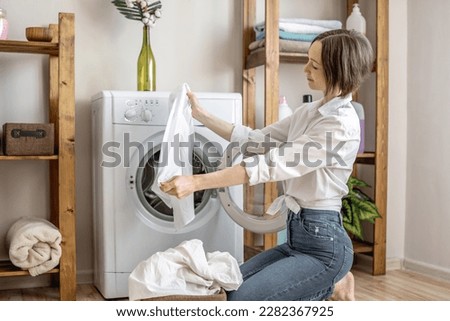A woman is rejoiceing of white laundry washed in a washing machine in a laundry. The concept of caring for things, cleaning and hygiene Royalty-Free Stock Photo #2282367925