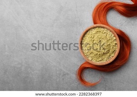 Henna powder and red strand on grey table, flat lay with space for text. Natural hair coloring
