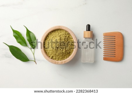Flat lay composition with henna powder and comb on white marble table. Hair care products