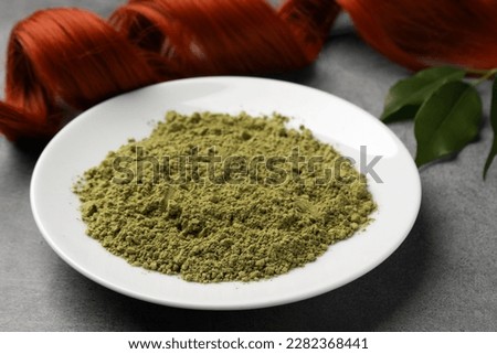 Henna powder and red strand on grey table, closeup. Natural hair coloring