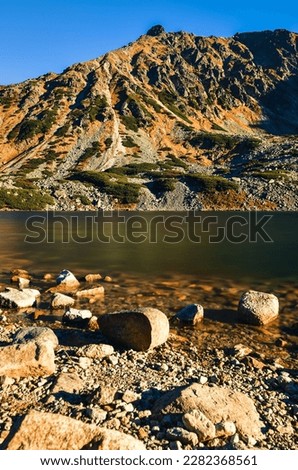 Beautiful summer mountain landscape. Mountain slopes reflecting in the lake. Photo taken in the Valley of Five Ponds in the Polish Tatra Mountains.