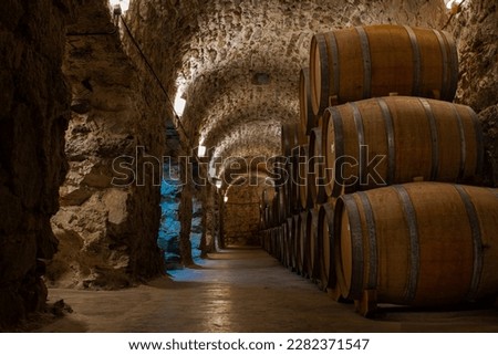 Underground brick and stone cellar with wooden barrels for storing malbec and tannat Royalty-Free Stock Photo #2282371547