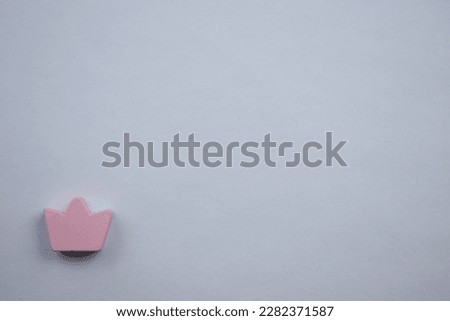pink crown.  A miniature pink crown, photographed from above, placed at the edge of a white background