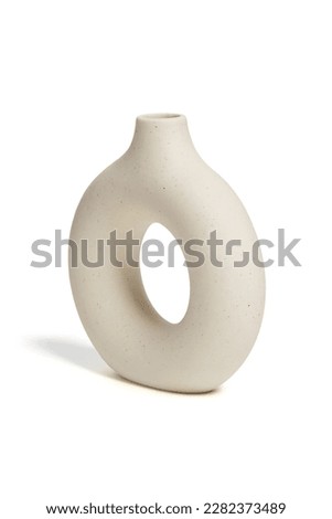 Close-up shot of a beige ceramic scandinavian vase. An empty donut vase is isolated on a white background. Home decor element. Side view. Royalty-Free Stock Photo #2282373489