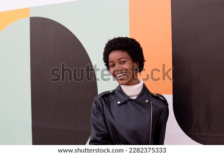 African girl with laptop and self phone smiling with multicolor background