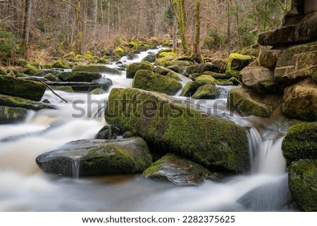 Long exposure of a waterfall and creek in the forest during winter