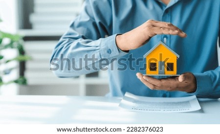 Broker agent with model toy house with documents signed purchase and sale contracts and mortgages including fire insurance