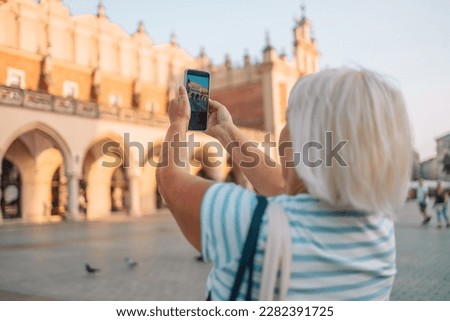 Beautiful Krakow market square, Poland, Europe. A hand taking photo of Sukiennice with smartphone, Krakow, Poland. High quality photo