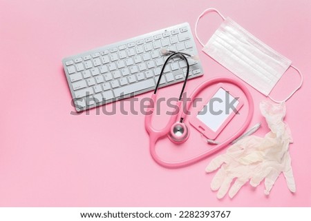 Stethoscope, pc keyboard, badge, medical mask and rubber gloves on pink background