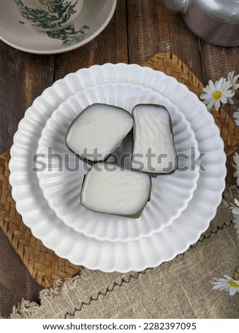 traditional Malaysian dessert called kuih tepung pelita or kuih tako on a rustic plate over a dark background. Coconut milk and flour prepared in banana leaves. Popular during fasting month Ramadan