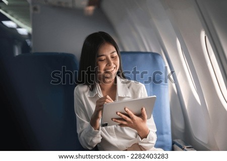 Beautiful asian travel woman watching movie on digital tablet in airplane