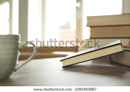 Education learning concept with opening book or textbook at home in office room, stack piles of literature text academic archive on reading desk and aisle of bookshelves in school study class room 