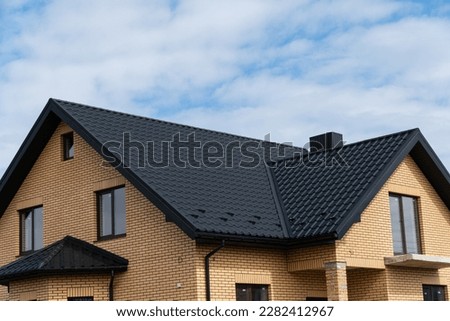 New brick house. The modern house with plastic windows and a black roof of corrugated sheet. Metal roofing. Royalty-Free Stock Photo #2282412967