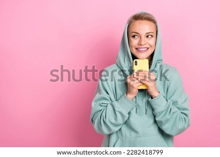 Photo of young addicted smartphone user shopaholic girl hold yellow smart phone touch chin look empty space amazon deal isolated on pink color background