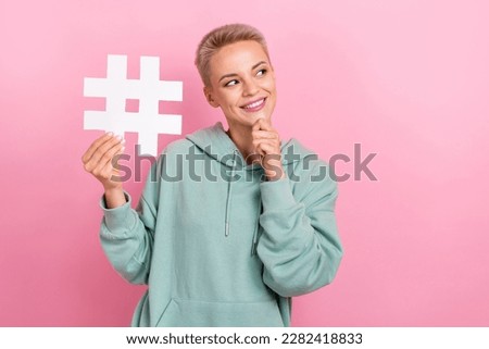 Photo portrait of lovely young lady hold hashtag touch chin look empty space dressed stylish khaki outfit isolated on pink color background