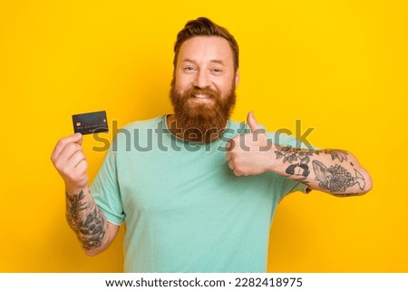 Portrait of positive satisfied man wear trendy green clothes hold plastic recommendation thumb up isolated on yellow color background