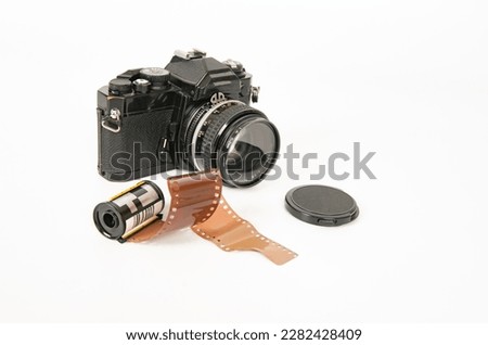 Photograph of a film camera and 35mm film on a white background