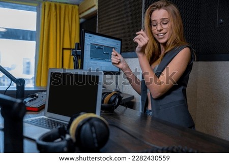 Pretty blonde long-haired woman at the radio station with headphones in hands