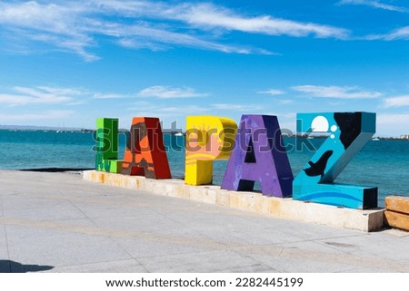 line of letters in peace, colors, sea in the background, iconic place in Mexico.