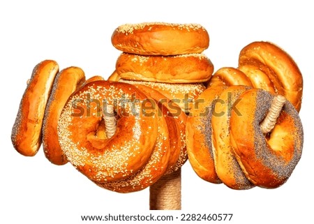 Appetizing bagels are topped with sesame seeds and poppy seeds hanging on a rack. Isolated on white Background. Selective focus.