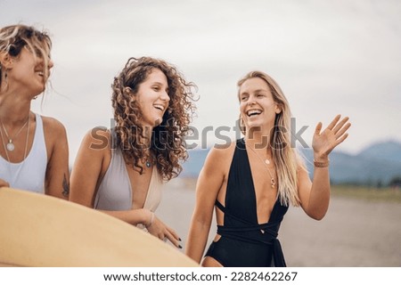 Three beautiful girl models in a bikini on the sea shore of a tropical island. Bronze tan, traveling, summer vacation. Female friends having fun outdoors on a hot summer day. Copy space.