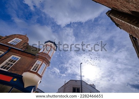 Birds flying above classical buildings in Cambridge, England. Dramatic sky and classic architecture.