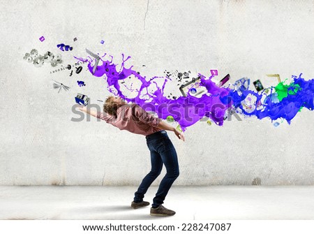 Young guy in casual evading from colorful splashes Royalty-Free Stock Photo #228247087