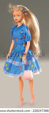 Small plastic baby girl toy. Isolated on grey background with shadow reflection.   Caucasian missy plaything with long blonde hair.