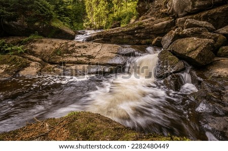 Amazing waterfall hidden deep in Jizera mountains, Czech Republic. Calm and peaceful place with water flowing in cascade river.