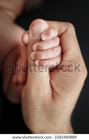 The newborn baby has a firm grip on the parent's finger after birth. Close-up little hand of child and palm of mother and father. Parenting, childcare and healthcare concept. Professional macro photo Royalty-Free Stock Photo #2282480889