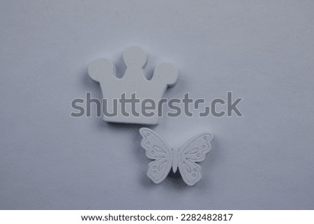 Differences, similarities, white butterfly and crown, photographed from above, placed on white background.  Differences, similarities.