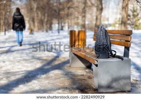 a man forgot his bag on a park bench. women's backpack is on a bench in the park. forgotten thing.  Royalty-Free Stock Photo #2282490929
