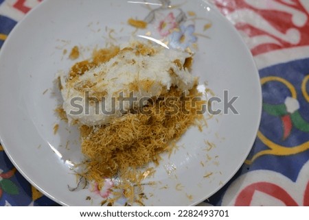 Konafa topped with whipped cream, raisins, walnuts, shredded coconut and stuffed with cream and fresh mango layer and soaked with honey sugar syrup, Eastern Turkish and Egyptian kunafa with manga